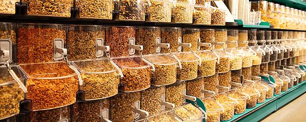 Plastic tubs line a wall full of bulk grains and nuts.