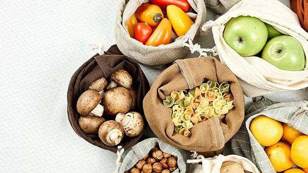 cloth bags holding a variety of fruits, vegetables, and grains