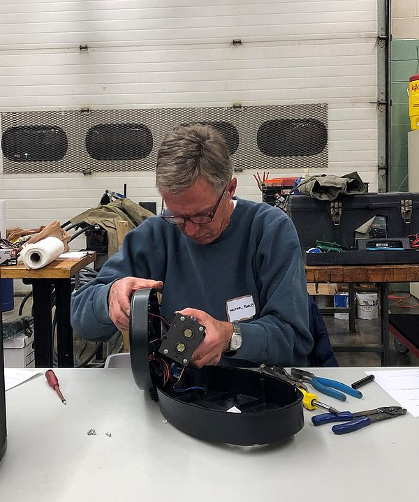 A volunteer disassembles an appliance.