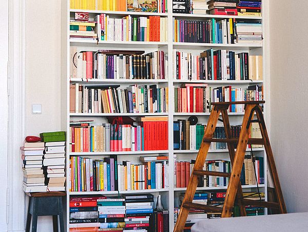 bookcase full of books with a rustic step ladder to the right